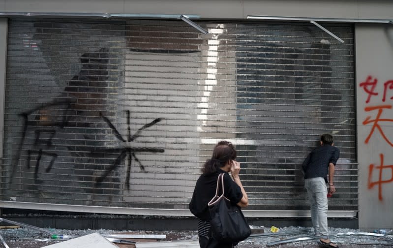 People inspect a shop which was vandalised during Sunday's anti-government protest in Hong Kong