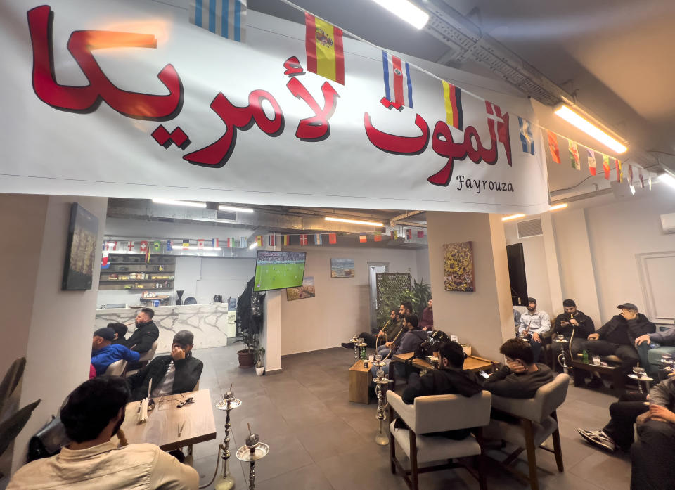 Lebanese fans of Iran's team, sit at a coffee shop under an Arabic banner that reads: "Death to America" as they watch the World Cup group B soccer match between Iran and the United States, in the Hezbollah stronghold in the southern suburbs of Beirut, Lebanon, Tuesday, Nov. 29, 2022. (AP Photo/Hussein Malla)