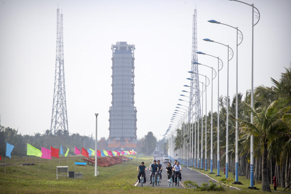 People ride bicycles along a road near a launch pad at the Wenchang Space Launch Site in Wenchang in southern China's Hainan province, Monday, Nov. 23, 2020. Chinese technicians were making final preparations Monday for a mission to bring back material from the moon's surface for the first time in nearly half a century — an undertaking that could boost human understanding of the moon and of the solar system more generally. (AP Photo/Mark Schiefelbein)