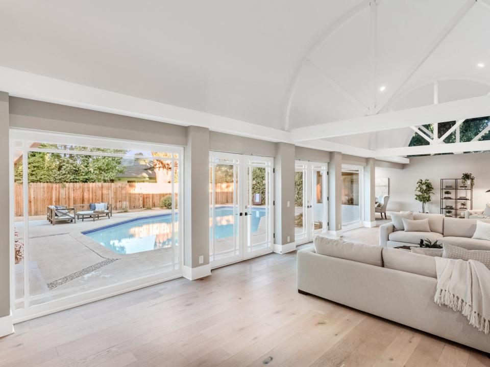 A living room with large windows and french doors, showing a pool.