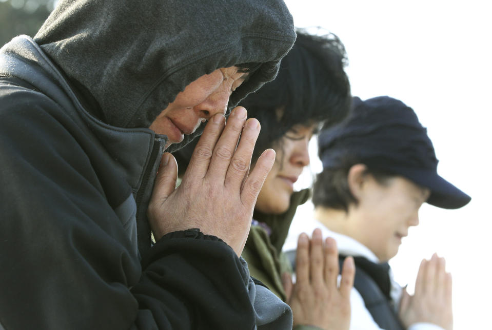 Relatives of passengers aboard the sunken ferry Sewol pray as they wait for their missing loved ones at a port in Jindo, South Korea, Monday, April 21, 2014. Divers continued the grim work of recovering bodies from inside the sunken South Korean ferry Monday, as a newly released transcript showed the ship was crippled by confusion and indecision well after it began listing. The transcript suggests that the chaos may have added to a death toll that could eventually exceed 300. (AP Photo/Ahn Young-joon)