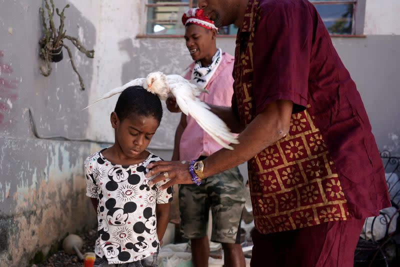 Jose Zamora, 8, has a dove rubbed over his body during the Afro-Cuban religion Santeria ceremony amid concerns about the spread of the coronavirus disease outbreak, in Havana