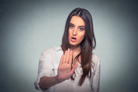 Woman holding out hand with serious look on her face.