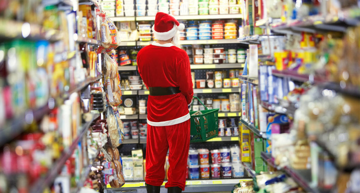 Man Christmas food shopping in supermarket with santa outfit on. (Getty Images)