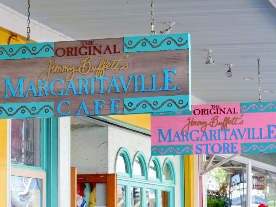 two signs hanging from a ceiling that read "The Original Jimmy Buffet's Margaritaville Cafe" and "The Original Jimmy Buffet's Margaritaville Store"