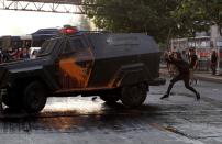 A demonstrator clashes with riot police during a protest against the increase in the subway ticket prices in Santiago