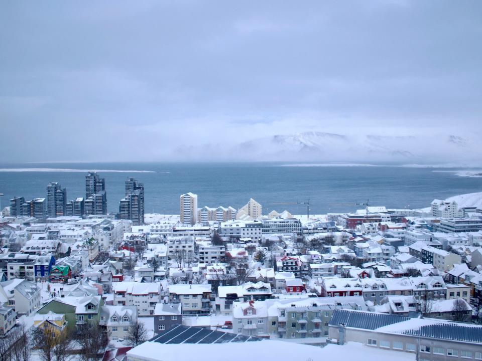 A photo taken on December 17, 2022 from the Hallgrimskirkja church shows a view over buildings in the city of Reykjavik, Iceland and Mount Esja (back) during snowfall. - The first snow started falling and intensified on December 17, covering the Icelandic capital in white.