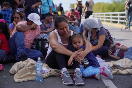 A woman from Honduras holds her three-year old daughter as she sits with a group who returned to Mexico to await their U.S. asylum hearing