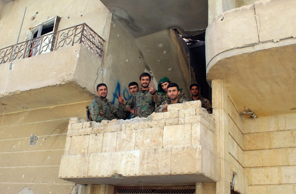 This picture taken on Monday provided by The Syrian Democratic Forces (SDF) shows Syrian Democratic Forces (SDF) fighters flashing victory signs at the front line where they have been battling against Isis. (Syrian Democratic Forces, via AP)