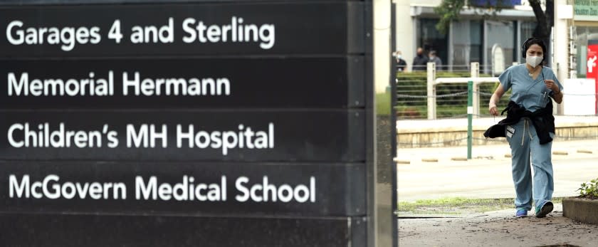 A healthcare professional walks through the Texas Medical Center Thursday, June 25, 2020, in Houston. The leaders of several Houston hospitals said they were opening new beds to accommodate an expected influx of patients with COVID-19, as coronavirus cases surge in the city and across the South. (AP Photo/David J. Phillip)