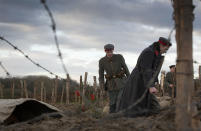 FILE - In this Dec. 20, 2014 file photo, re-enactors dressed in World War I German uniforms walk into a reconstructed trench during a re-enactment in Ploegsteert, Belgium. German Chancellor Angela Merkel will mark the 100th anniversary of the end of World War I on French soil, and President Frank-Walter Steinmeier will be in London’s Westminster Abbey for a ceremony with the queen. But in Germany, there are no national commemorations planned for the centenary of the Nov. 11 armistice that brought an end to the bloody conflict that killed more than 2 million of its troops and left 4 million wounded. That’s because the armistice did not bring peace to Germany. (AP Photo/Virginia Mayo, File)