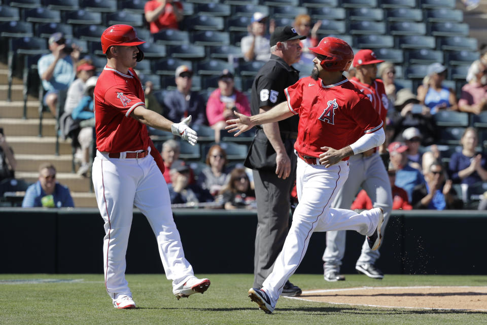 Los Angeles Angels' Mike Trout, left, and Anthony Rendon react after scoring during the first inning of a spring training baseball game against the Cincinnati Reds, Tuesday, Feb. 25, 2020, in Tempe, Ariz. (AP Photo/Darron Cummings)