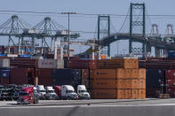 In this Tuesday, Oct. 19, 2021, photo trucks line up next to containers at the Port of Los Angeles in san Pedro, Calif. The Vincent Thomas Bridge suspension bridge, crossing the Los Angeles Harbor links San Pedro with Terminal Island. California Gov. Gavin Newsom on Wednesday, Oct. 20, 2021 issued an order that aims to ease bottlenecks at the ports of Los Angeles and Long Beach that have spilled over into neighborhoods where cargo trucks are clogging residential streets. Last week the White House allowed the ports complex to become a 24-hour operation in an effort to break the logjam and reduce shipping delays. (AP Photo/Damian Dovarganes)