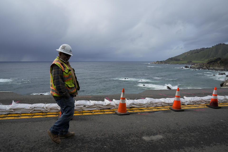 A construction worker walks past the collapsed section of the southbound lane of Highway 1 at Rocky Creek Bridge, Thursday, April 4, 2024, in Big Sur, Calif. The break has caused the closure of the scenic road. (AP Photo/Godofredo A. Vásquez)