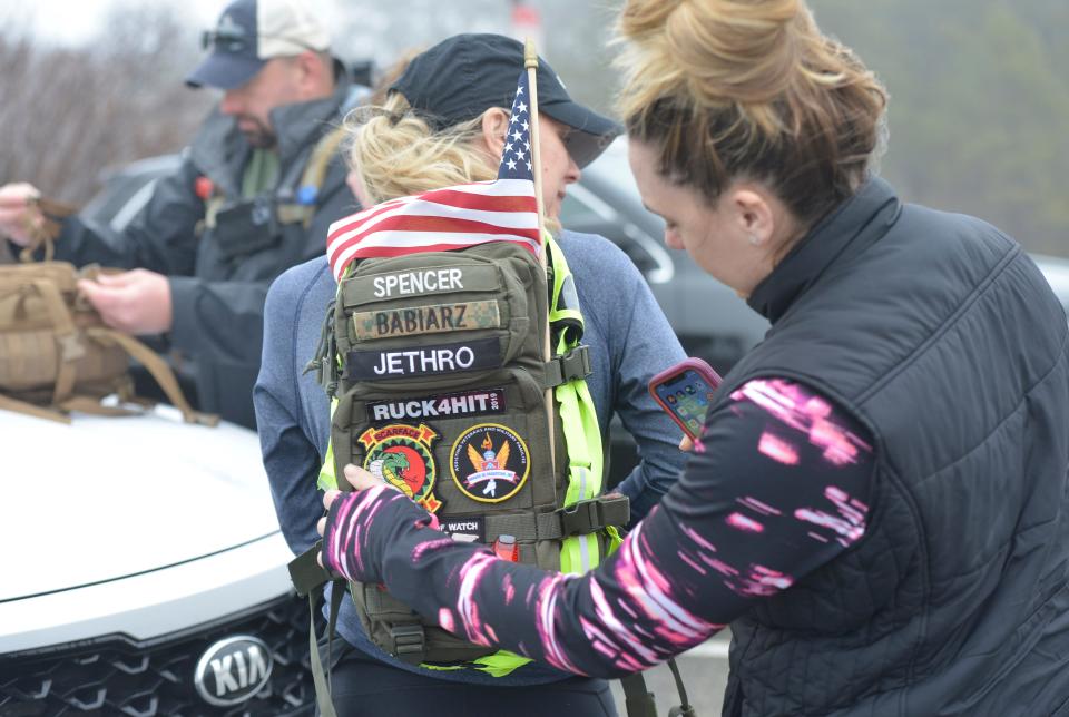 Megan Carroll, right, helps Nicole Spencer with her rucksack, symbolizing the burdens that the military and veterans carry.