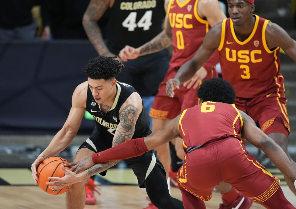 Colorado guard KJ Simpson, left, picks up the ball as Southern California guard Bronny James, front right, and forward Vincent Iwuchukwu (3) defend in the first half of an NCAA college basketball game Saturday, Jan. 13, 2024, in Boulder, Colo. (AP Photo/David Zalubowski)