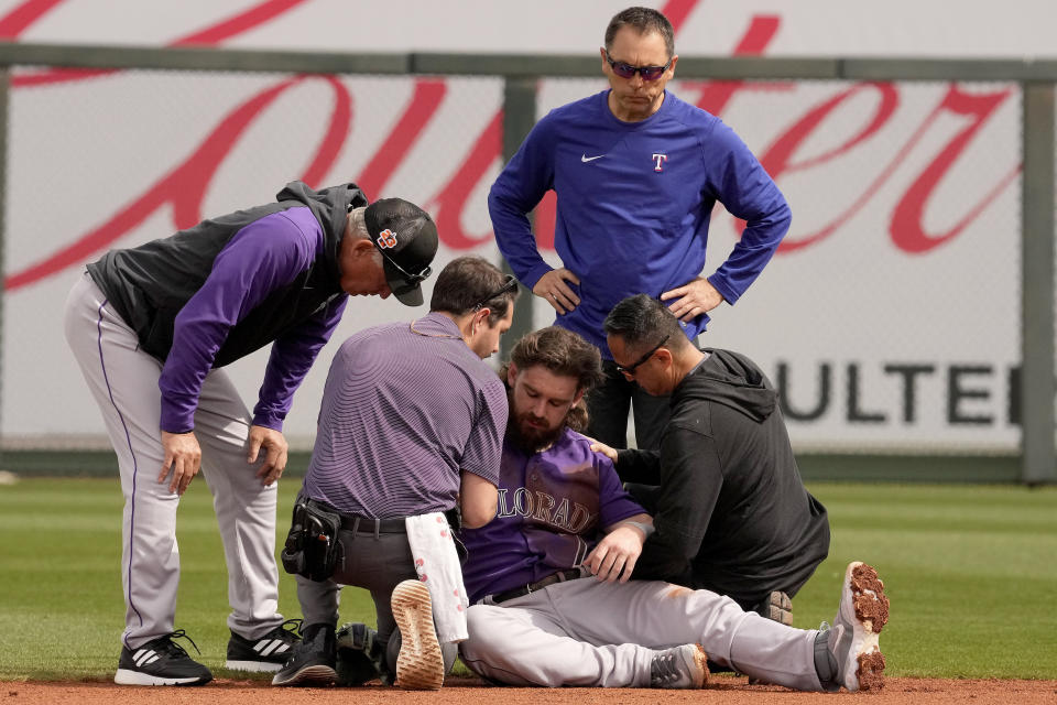 Colorado Rockies manager Bud Black, left, and other personnel tend to second baseman Brendan Rodgers after he was injured during the first inning of a spring training baseball game against the Texas Rangers Tuesday, Feb. 28, 2023, in Surprise, Ariz. (AP Photo/Charlie Riedel)
