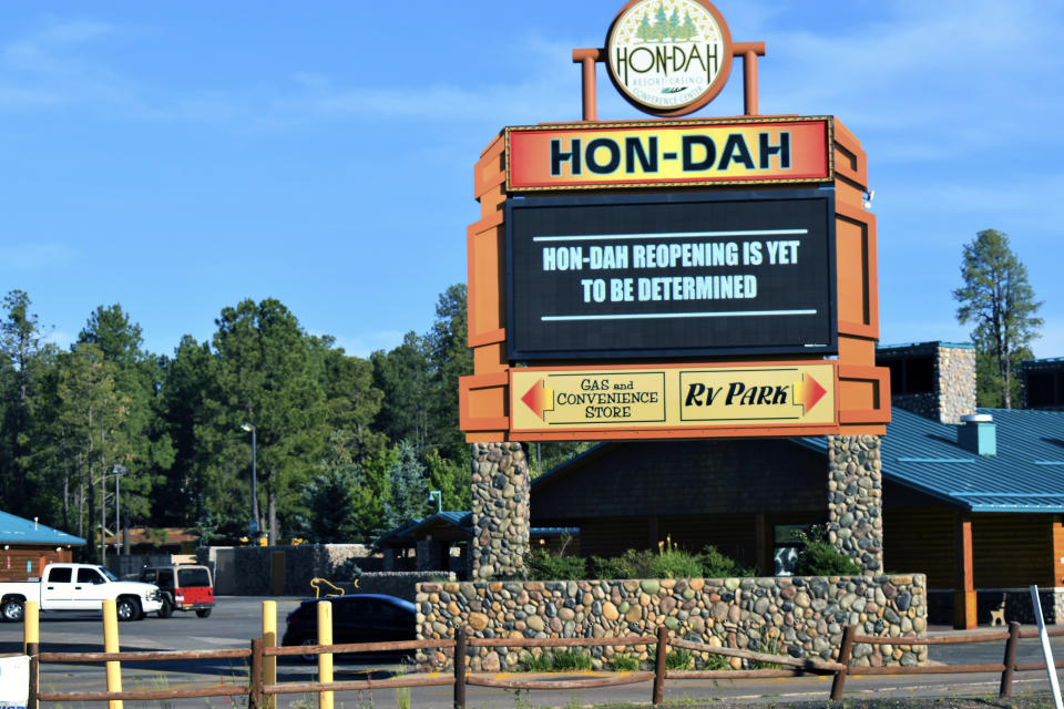 In this Thursday, June 25, 2020 photo provided by C.M. Clay, the sign at Hon-Dah Resort Casino in Pinetop, Ariz., informs the public that a reopening date has yet to be determined. The White Mountain Apache Tribe, which owns the casino, is implementing weekend lockdowns to help slow the spread of the coronavirus. (C.M. Clay/White Mountain Apache Tribe via AP)