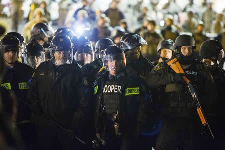 Police officers and National Guard soldiers watch protesters gathered to demand justice for the killing of 18-year-old Michael Brown, outside the Ferguson Police Department in Ferguson, Missouri November 28, 2014. REUTERS/Lucas Jackson