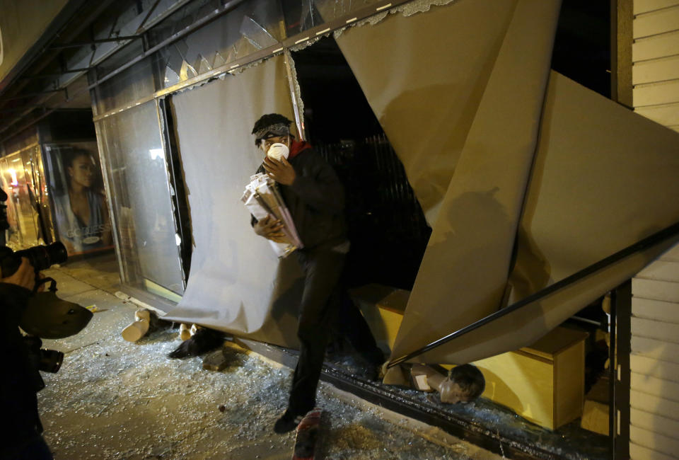 <p>A protester walks out of a store with goods after the announcement of the grand jury decision Monday, Nov. 24, 2014, in Ferguson, Mo. A grand jury has decided not to indict Ferguson police officer Darren Wilson in the death of Michael Brown, the unarmed, black 18-year-old whose fatal shooting sparked sometimes violent protests. (AP Photo/David Goldman) </p>