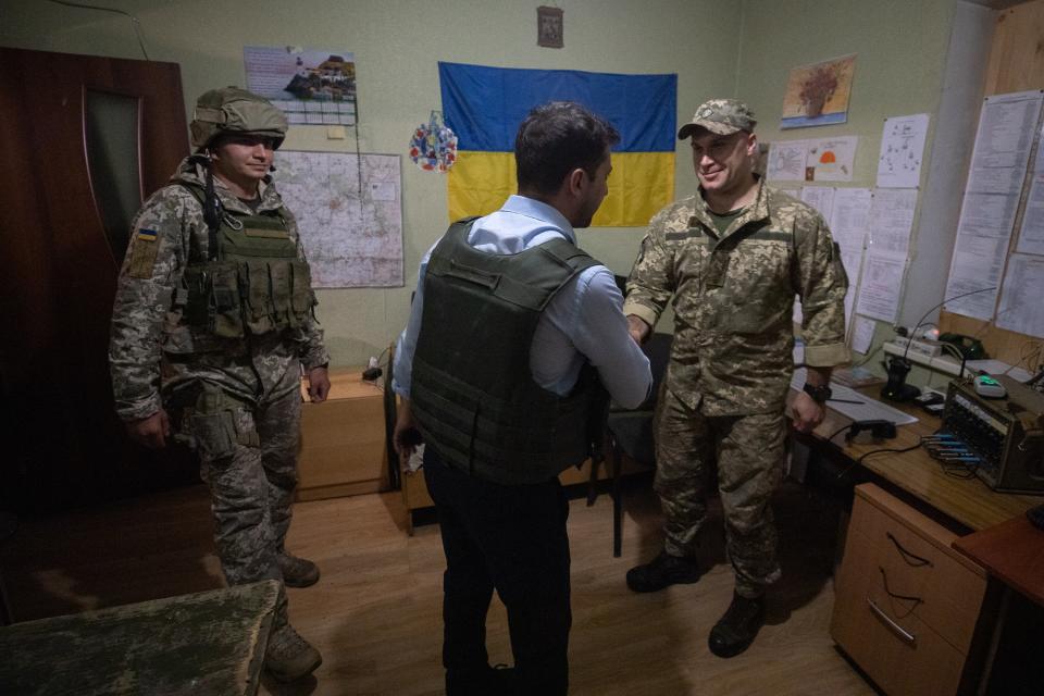 Ukrainian President Volodymyr Zelenskiy, back to a camera, greets a serviceman as he visits the war-hit Luhansk region, eastern Ukraine, Monday, May 27, 2019. (Ukrainian Presidential Press Office via AP)