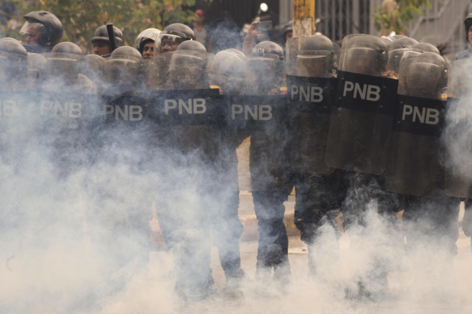 Riot police stand amid tear gas as they face off with student protesters from the Venezuela Central University demanding an increased budget for scholarships and to reopen the university cafeteria in Caracas, Venezuela, Wednesday, Nov. 21, 2018. (AP Photo/Ariana Cubillos)