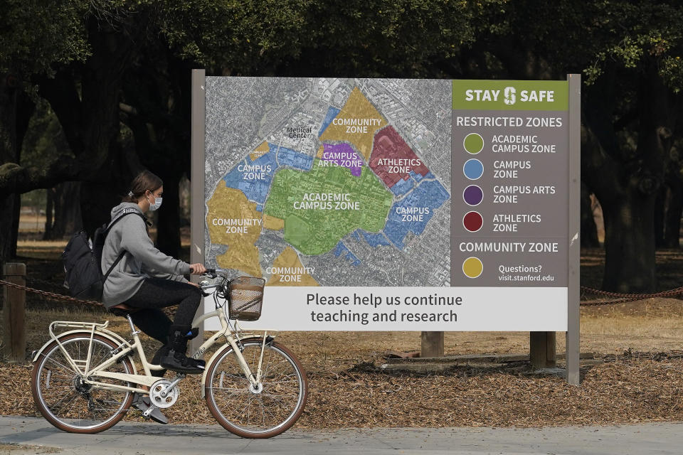 A bicyclist rides past a sign showing restricted zones around the Stanford University campus in Stanford, Calif., Wednesday, Sept. 2, 2020. With the coronavirus spreading through colleges at alarming rates, universities are scrambling to find quarantine locations in dormitory buildings and off-campus properties to isolate the thousands of students who have caught COVID-19 or been exposed to it. (AP Photo/Jeff Chiu)