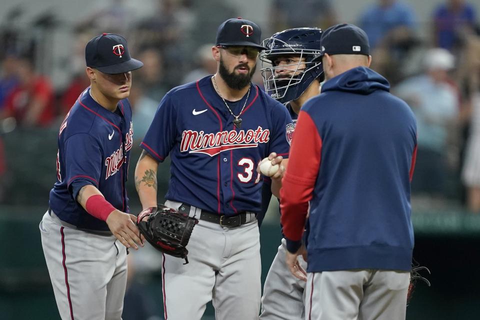 Minnesota Twins starting pitcher Devin Smeltzer (31) turns the ball over to manager Rocco Baldelli, right, as Jose Miranda, left rear, and Gary Sanchez, right rear, stand by on the mound in the fourth inning of a baseball game against the Texas Rangers, Saturday, July 9, 2022, in Arlington, Texas. (AP Photo/Tony Gutierrez)