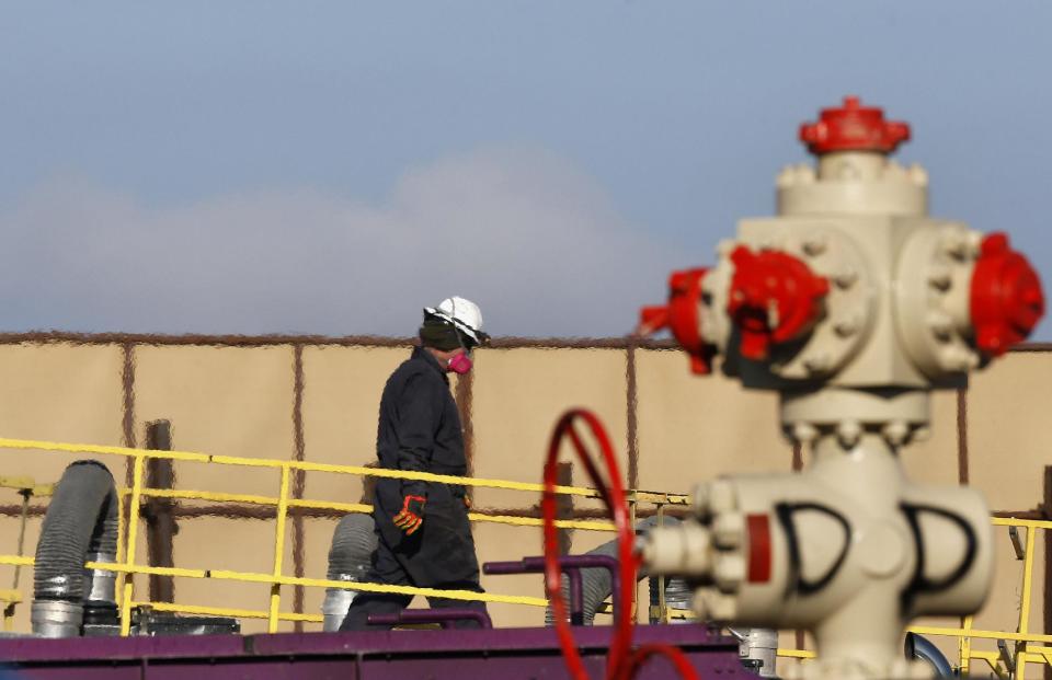 FILE - This March 25, 2014 file photo shows heat from machinery distorts the air as a worker watches over a hydraulic fracturing operation at an Encana Corp. gas well near Mead, Colo. The energy boom is scrambling national politics. Democrats are split between environmentalists and business and labor groups. Some deeply-conservative areas are allying with conservationists against fracking, the technique largely responsible for the surge. (AP Photo/Brennan Linsley, File)