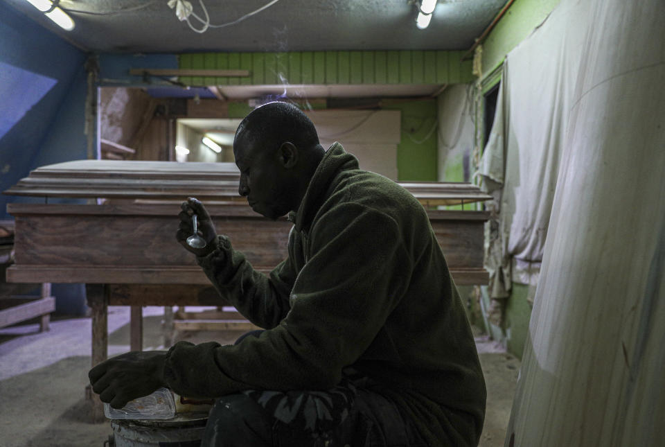 Haitian migrant and coffin factory worker Francois Joseph eats his lunch at the Bergut Funeral Services factory in Santiago, Chile, Thursday, June 18, 2020. The coffin production has had to increase up to 120%, according to Nicolas Bergerie, owner of the factory. His more basic coffin model is called the COVID model and is made to cope with the increase of deaths during the coronavirus pandemic. (AP Photo/Esteban Felix)