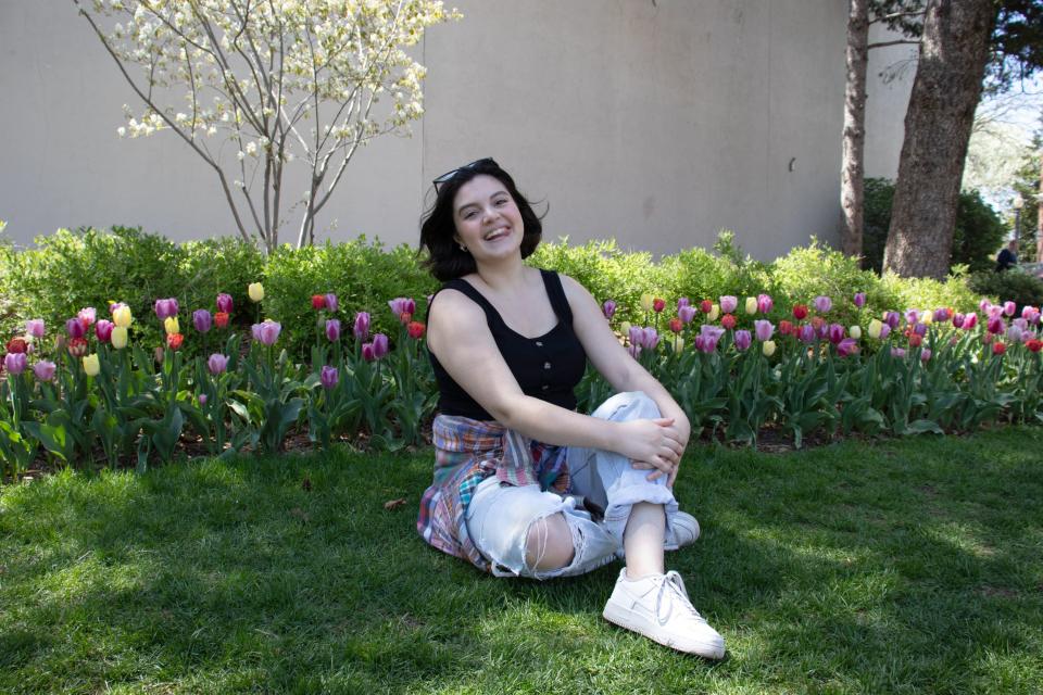 Insider's Gabi Stevenson sitting and smiling front of tulips in a black top and jeans