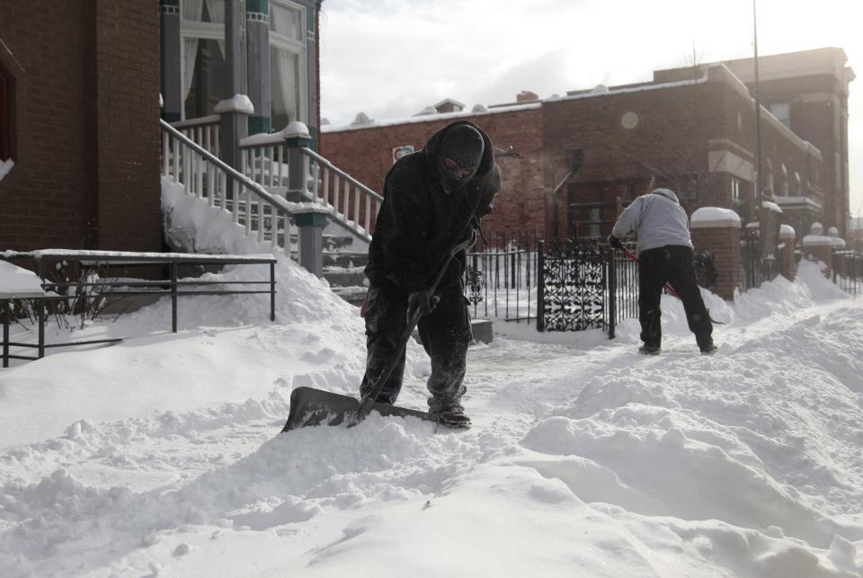 Laborers shovel the snow off of the sidewalk in the midtown neighborhood of Detroit