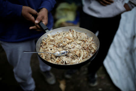 Syrian refugee Bashar Wakaa holds a pan with chicken, provided by the Greek authorities at a makeshift camp for refugees and migrants next to the Moria camp on the island of Lesbos, Greece, November 30, 2017. REUTERS/Alkis Konstantinidis