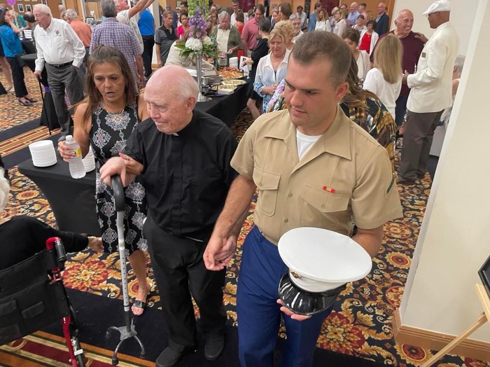 Monsignor David Page, led by PFC Marine Austin Rolison and Jennifer Rolison, his mother.