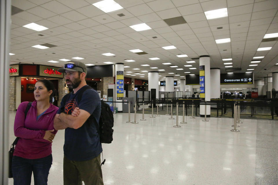 Confused travelers look to find their concourse as they walk past a closed down terminal at the Miami International Airport on Saturday, Jan. 12, 2019, in Miami. (Photo credit: AP Photo/Brynn Anderson)
