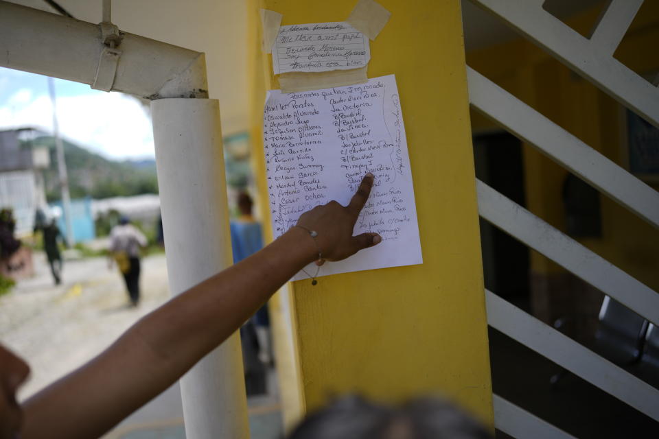 A person points to a list of names of people, affected by flooding, who were checked into a community center where they are given first aid or transported to another city for medical treatment, in Las Tejerias, Venezuela, Monday, Oct. 10, 2022. The bodies of victims are also brought here, after a fatal landslide fueled by flooding and days of torrential rain swept through this town in central Venezuela. (AP Photo/Matias Delacroix)