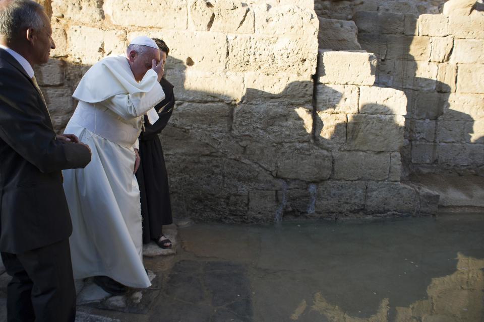 Pope Francis prays at the edge of Jordan River