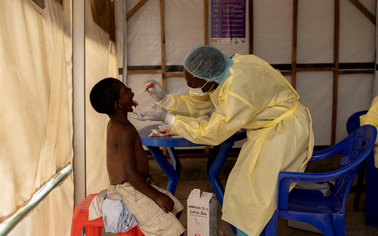 A health worker collects a sample from a child suspected of being infected with mpox