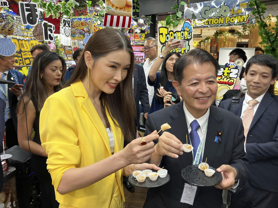 Japanese Agriculture Minister Ichiro Miyashita, front right, and Malaysian celebrity Amber Chia, front left, attend an event at Japanese store, Don Don Donki in Kuala Lumpur Wednesday, Oct. 4, 2023 to promote the safety and deliciousness of Japanese scallops to shoppers. Japan hopes to resolve the issue of China's ban on its seafood within the scope of the World Trade Organization ambit and will hold food fairs overseas to bolster seafood exports amid safety concerns over the release of treated water from the Fukushima Daiichi nuclear plant, Miyashita said Wednesday. (AP Photo/Eileen Ng)