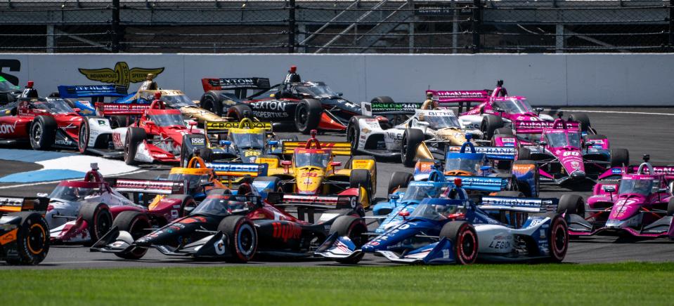 The field of IndyCar drivers navigate into the first turn after taking the green flag during the Gallagher Grand Prix at the Indianapolis Motor Speedway, Saturday, Aug. 12, 2023, in Speedway, Ind.