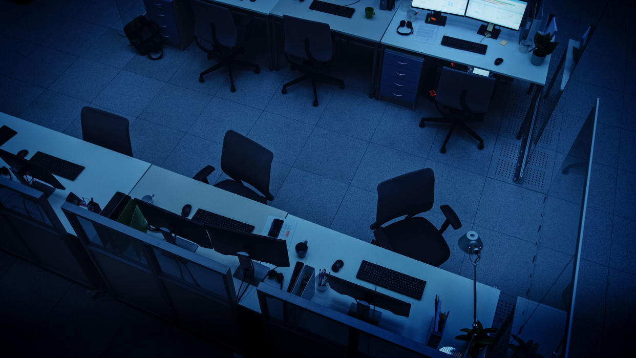 Elevated High Angle Shot of Dark Empty Office with Wheelchairs, Desks and Computers. Concept of Finishing Working Alone Late at Night.