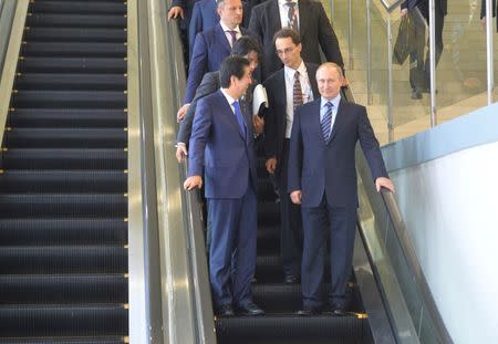 Russian President Vladimir Putin (R, front) and Japanese Prime Minister Shinzo Abe (L, front) ride down an escalator during their meeting on the sidelines of Eastern Economic Forum in Vladivostok, Russia, September 2, 2016. Sputnik/Kremlin/Alexei Druzhinin/via REUTERS