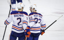 Edmonton Oilers defenseman Evan Bouchard (2) celebrates his goal against the Calgary Flames with forward Ryan Nugent-Hopkins (93) during the third period of an NHL hockey game Saturday, April 6, 2024, in Calgary, Alberta. (Jeff McIntosh/The Canadian Press via AP)