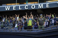 Fans sitting in socially distanced groups perform the "Boom Boom Clap" cheer at the start of an MLS soccer match between the Seattle Sounders and Minnesota United, Friday, April 16, 2021, in Seattle. The match was the Sounders' home-opener, and the first home game played in front of fans in more than a year. (AP Photo/Ted S. Warren)