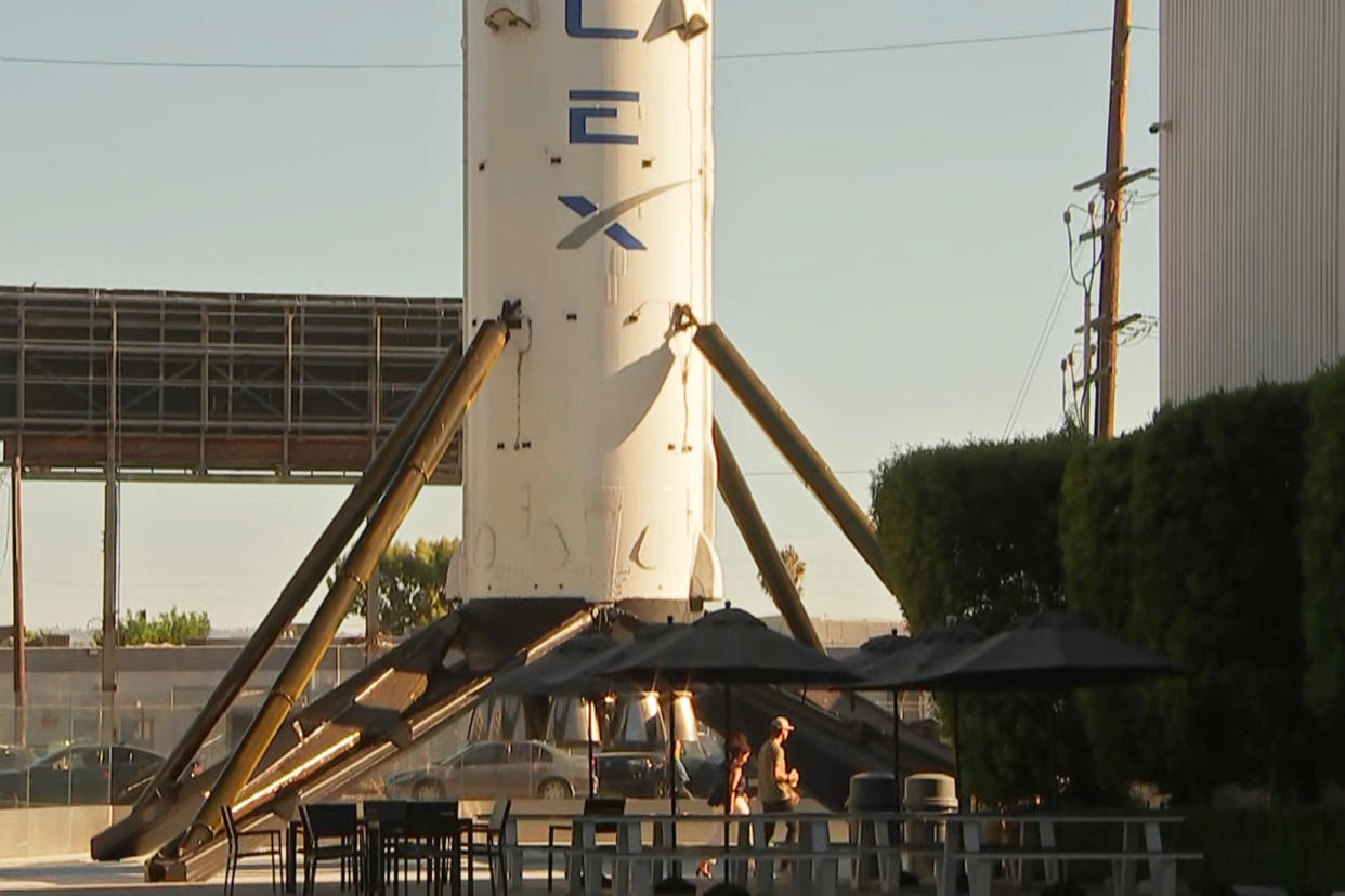 People walk past a SpaceX rocket on display outside SpaceX headquarters in Hawthorne, Calif. (NBC News)