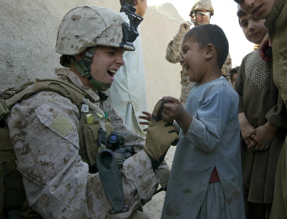 MUSA QALA, AFGHANISTAN - NOVEMBER 21: (SPAIN OUT, FRANCE OUT, AFP OUT) Sargent Sheena Adams, 25, US Marine with the FET (Female Engagement Team) 1st Battalion 8th Marines, Regimental Combat team II gets attention from some Afghan boys while on patrol on November 21, 2010 in Musa Qala, Afghanistan. There are 48 women presently working along the volatile front lines of the war in Afghanistan deployed as the second Female Engagement team participating in a more active role, gaining access where men can't. The women, many who volunteer for the 6.5 month deployment take a 10 week course at Camp Pendleton in California where they are trained for any possible situation, including learning Afghan customs and basic Pashtun language. (Photo by Paula Bronstein/Getty Images)