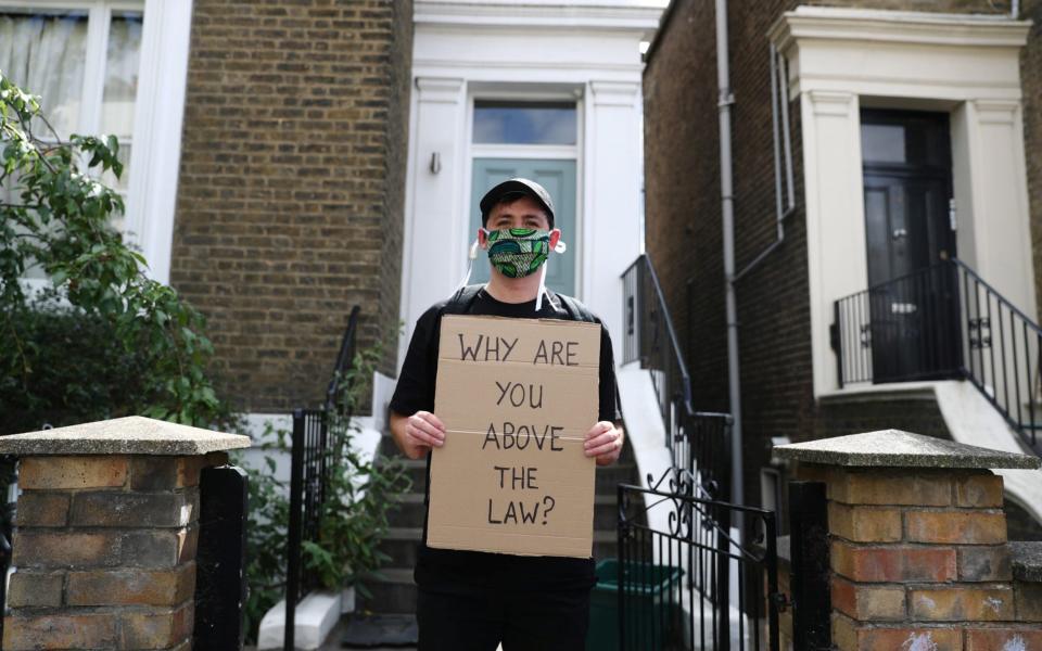 Ben holds a sign as he protests outside the house of Dominic Cummings in London, following the outbreak of the coronavirus disease (COVID-19), London - REUTERS