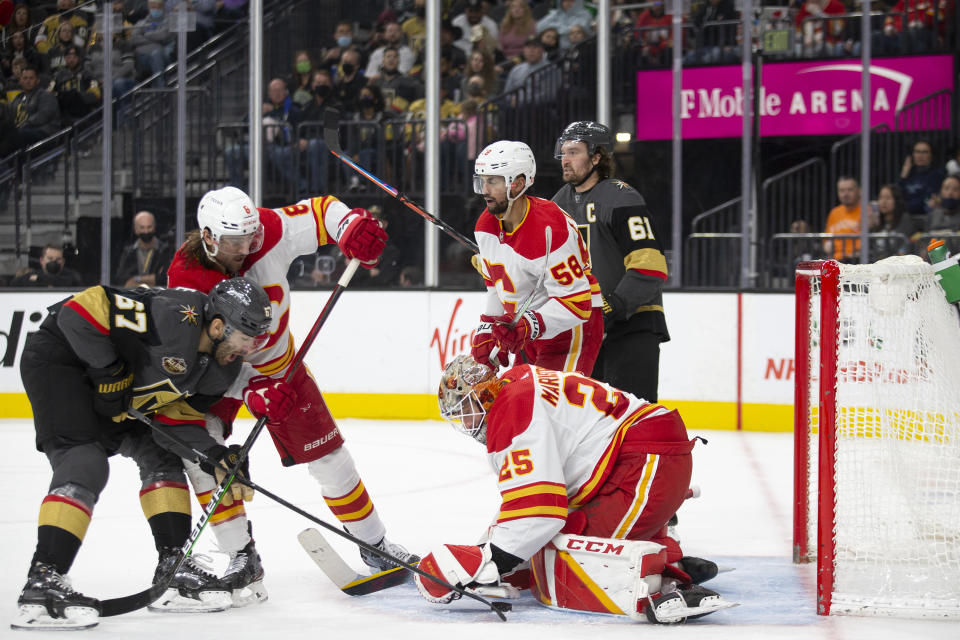 Calgary Flames goaltender Jacob Markstrom (25) saves a shot on goal by Vegas Golden Knights left wing Max Pacioretty (67) while Calgary Flames defenseman Christopher Tanev (8) defends during the second period of an NHL hockey game Sunday, Dec. 5, 2021, in Las Vegas. Calgary Flames defenseman Oliver Kylington (58) and Vegas Golden Knights right wing Mark Stone (61) are behind. (AP Photo/Ellen Schmidt)