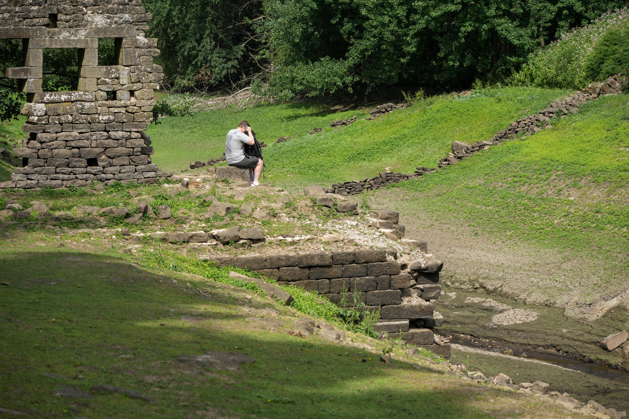 HARROGATE, ENGLAND - JULY 19: People sit on the remnants of the 17th century village of West End which can be seen after water levels in the Thruscross reservoir are partially depleted in the heatwave on July 19, 2022 in Harrogate, England. Yorkshire Water, the regional utility, warned residents to use water wisely during the heatwave, adding that the area has had below average rainfall since last autumn. (Photo by Christopher Furlong/Getty Images)