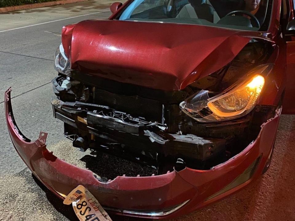 a red car sits on the road with its front bumper damaged